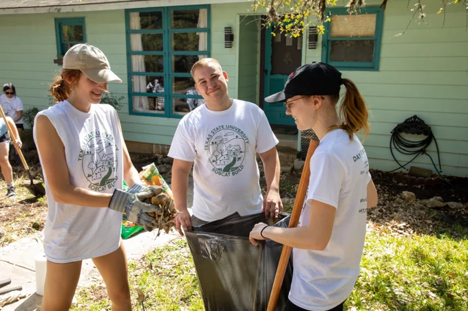 TXST students collecting leaves outside a residence during Bobcat Build