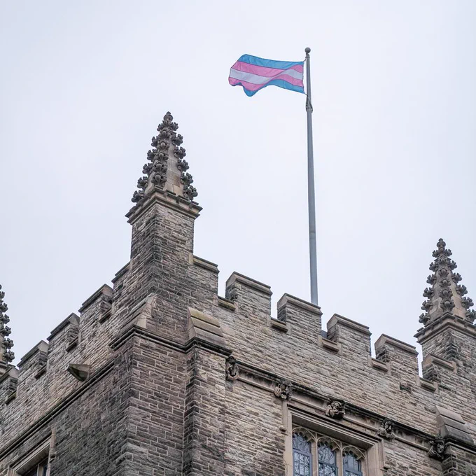The blue, pink and grey striped trans pride flag flies above University Hall at McMaster. 