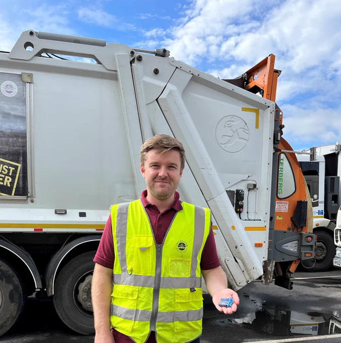 A member of the waste collection crew holding some batteries