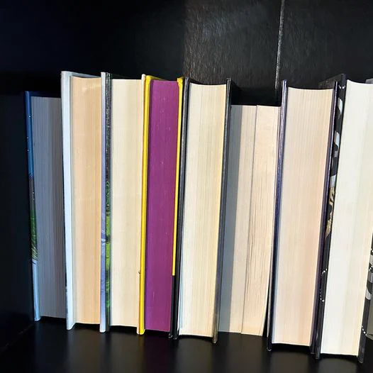 description: books on a Library bookshelf with their pages facing out instead of their spines.