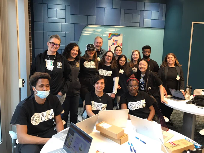 Deaf and hard of hearing students participate in the hackathon and are seated around a round table. Jose, their instructor, Jill Stark, Shireen Hafeez, Rachel Arfa and Sarah Faber of Parks join the students in smiling for the camera.