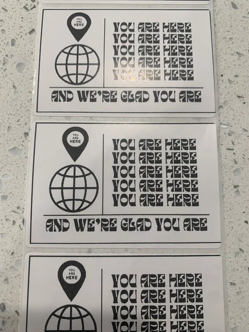 Image of a sticker that reads “you are here and we’re glad you are”
