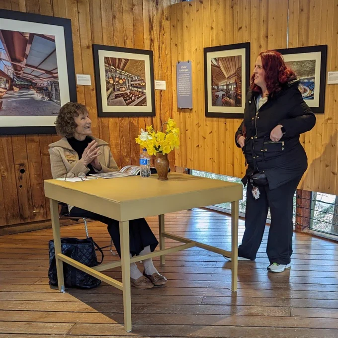 Visitor and volunteer talk while looking at Andrew Pielage's Sacred Spaces exhibition in Speyer Gallery.