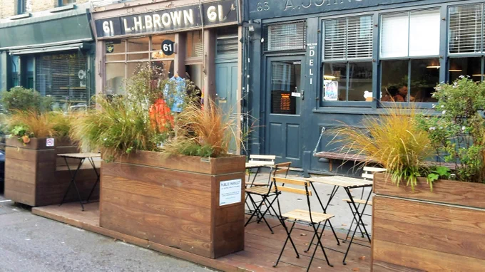 An example photo of a parklet with chairs, tables and planters.