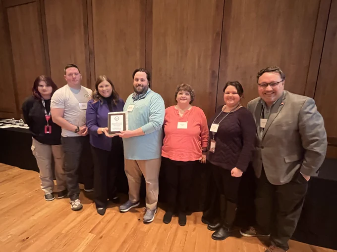 DOA staff gather around an award received for highest percent participation for agencies with 901  employees in Partners in Giving campaign.