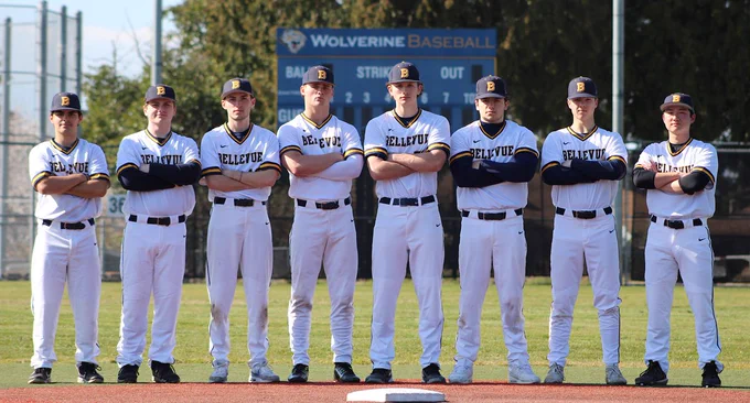 Eight baseball players standing in the infield, shoulder to shoulder, in the sunshine. 
