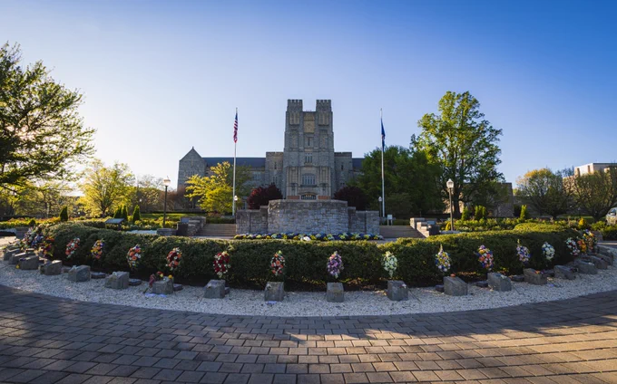 An image shows the April 16 Memorial in front of Burruss Hall at dusk.

