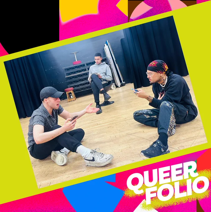 Three young actors rehearse in a drama studio. One sits on a chair, legs crossed. Two sit on the floor facing each other holding up their mobile phones.