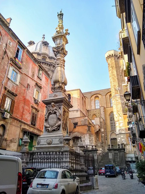 A photo of an old Italian city with monuments, cars and old colourful buildings