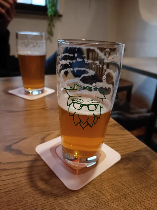 Glass of beer, slightly less than half full, and in the background another glass of beer which is included in the picture mostly to signal that I am not by myself but actually have a pal with me