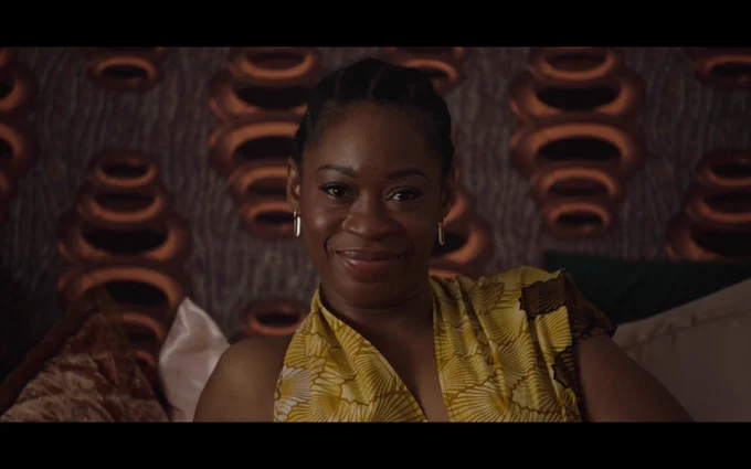 Oluniké Adeliyi smiling at the camera while sitting in bed 
