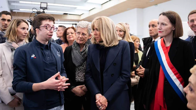 Photographie sur laquelle Geneviève Darrieussecq, Brigitte Macron, Marie Amélie Le Fur et une élue échangent avec un homme en situation de handicap. Ce dernier porte une veste bleu marine du "Coq sportif".

En arrière-plan, d'autres personnes sont présentes dans la délégation.