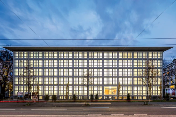 Ansicht der ZHB Sempacherstrasse am Abend mit Blick auf den beleuchteten Magazintrakt/Freihandbereich mit seinen typischen, mosaikartigen Fenstern. Foto von Daniela Burkart burkart.lu