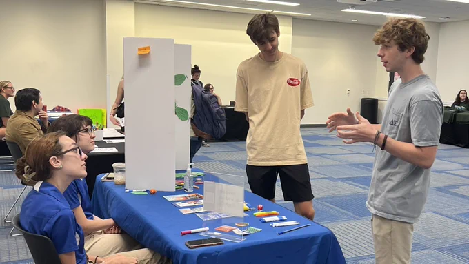 Two students talk with two students tabling at the Dare to Explore Disability event.