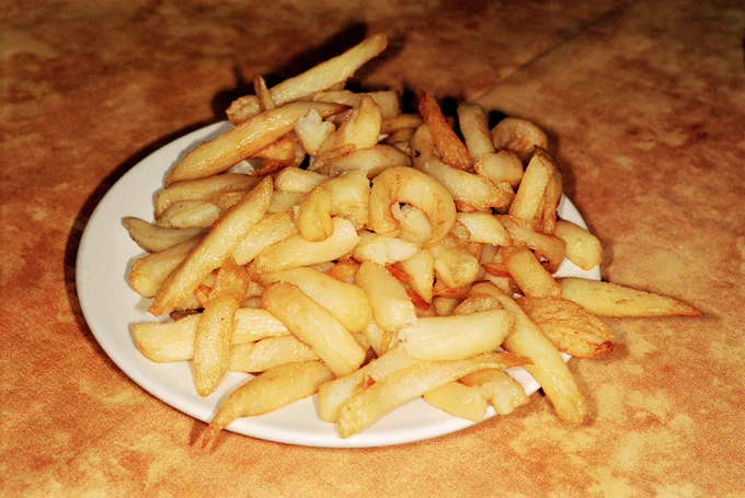 A plate of soggy fries sitting on a white plate.