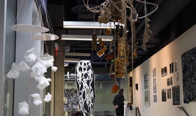 Various paintings and sculptures hang in a gallery.