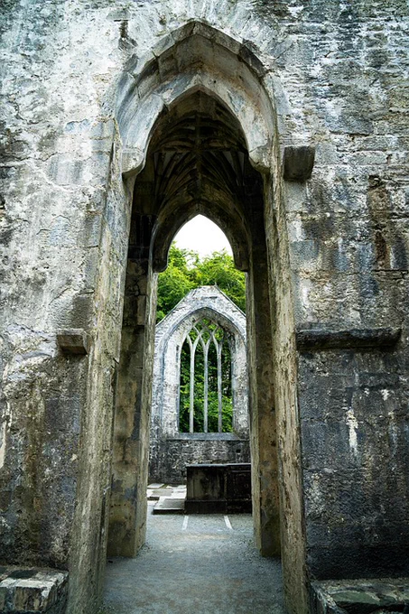 A photo of ghotic ruins with bright green trees shining through