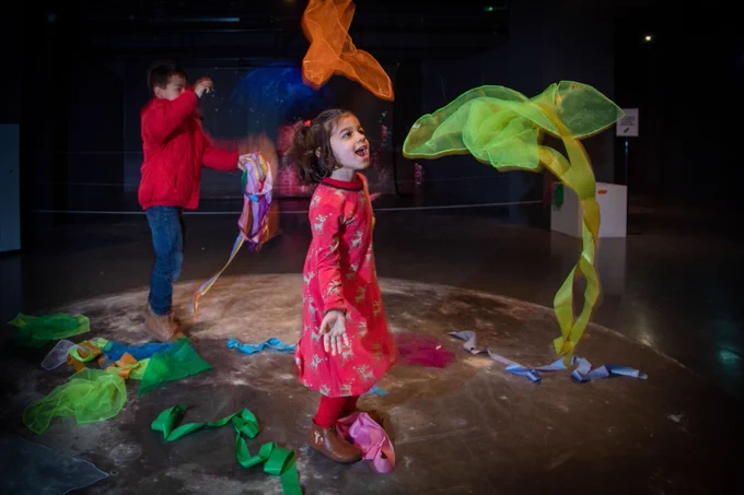 Children throw fabric scarves into the air to interact with the Giant Leaps exhibit.