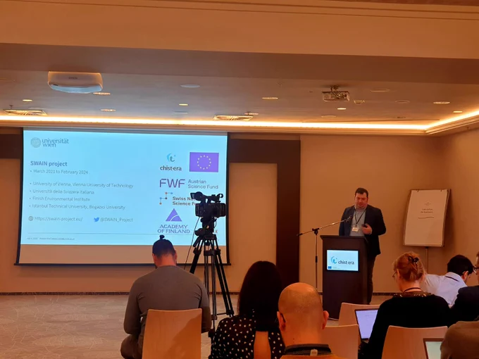 Atakan Aral presents about SWAIN project's success story in open science at the CHIST-ERA project seminar 2023 in Bratislava. The slide shows project information, including partners and funders.