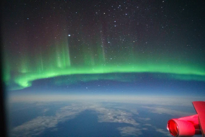 A view of aurora australis from SOFIA during the 2022 New Zealand deployment.

A neon green glow goes across the image near its center, with rays of green pointing upward. Above it is a black, star-speckled sky, and below it, in the bottom third of the image, is the Earth's horizon. 

Image taken by Ian Griffin.