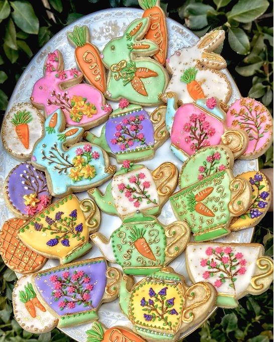 A tray of colorful cookies ornately decorated to look like teapots, teacups, bunnies, and carrots.
