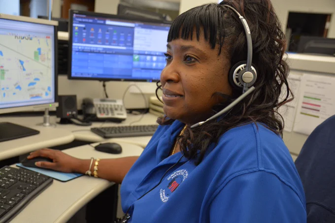 Dispatcher wearing a headset, sitting in front of multiple computer screens