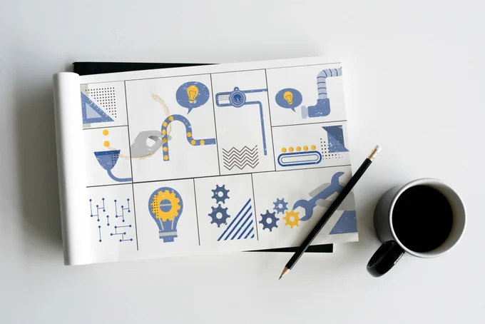 Composição: um caderno de desenho com ilustrações, um lápis sobre o caderno e uma xícara de café ao lado. Fundo branco. As ilustrações são: uma régua triangular, uma lâmpada com engrenagem no centro, engrenagens, uma chave inglesa, uma plataforma rolante de produção entre outras similares.