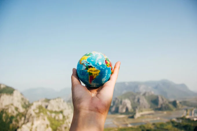 A hand holding a small model of the world