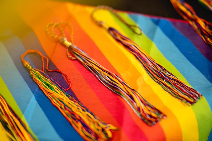 Rainbow tassles on top of a rainbow flag covering a table