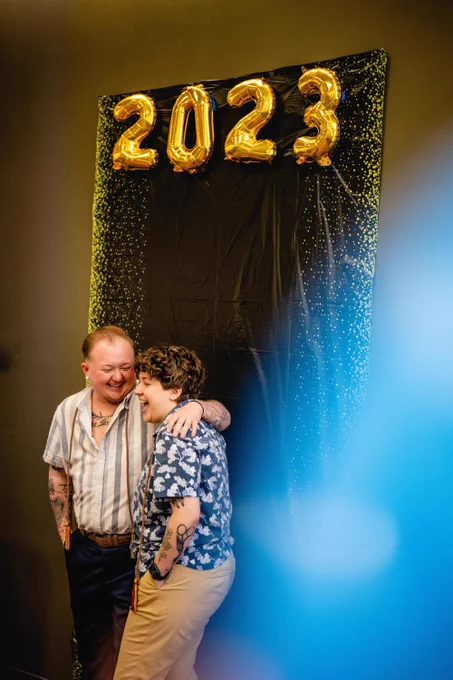 Gold 2023 balloons float as two Spartans laugh with their arms around each other 