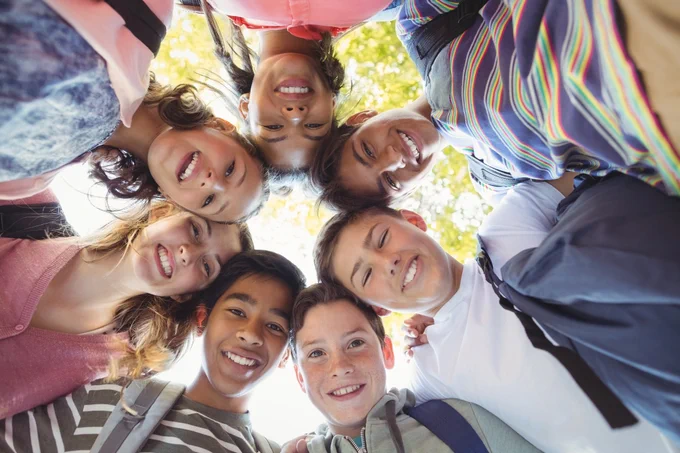 A group of seven students formed a huddle and smiled at the camera.
