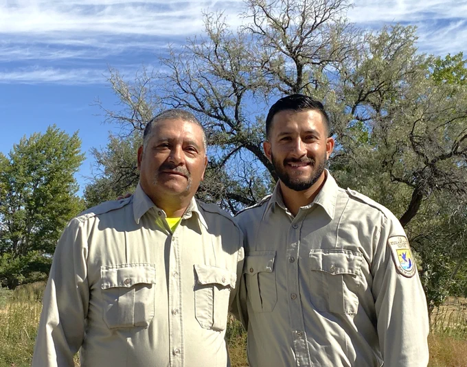 Jesus and Miguel smiling at the camera with trees behind them.