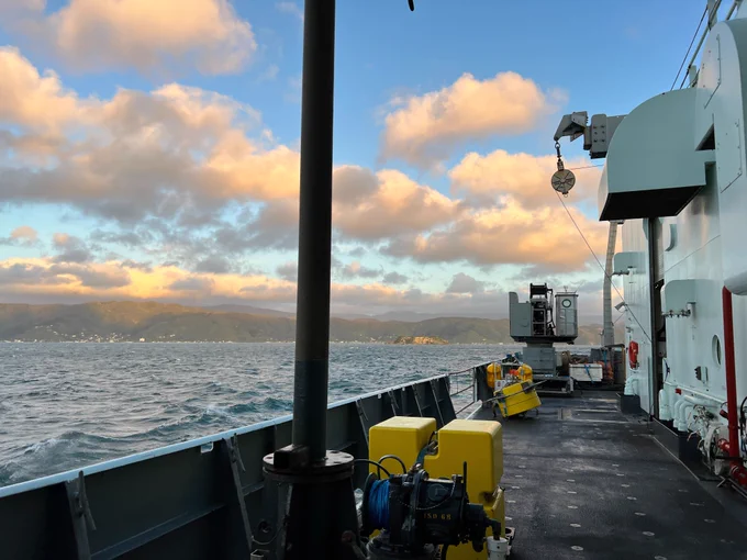 Sunset view from the deck of the Thompson as we returned to Wellington. On the righthand side of the image is the deck of the ship with two yellow floats. To the right is the water and hills in the distance.