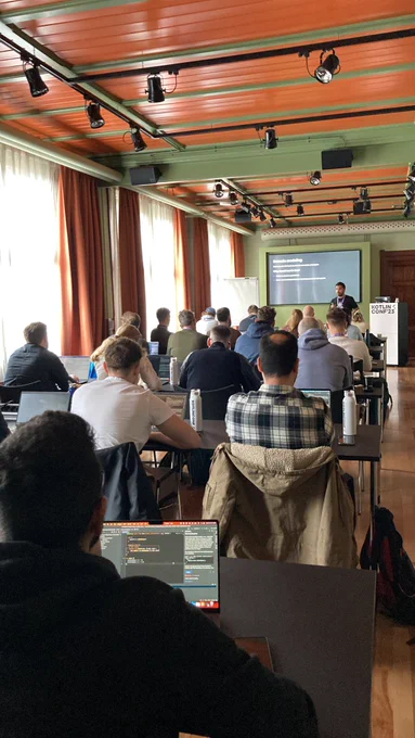 The picture features attendees of a workshop listening to Paco Diaz on domain modeling at KotlinConf