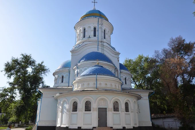 A photo of a white orthodox church with blue domes on a sunny day