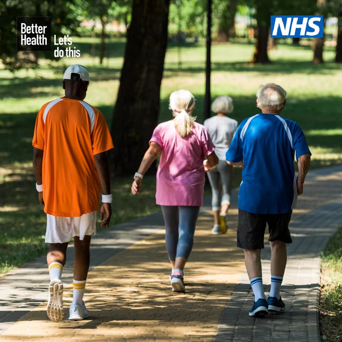 Group of 4 middle age to elderly people walking briskly in a park. Better Health logo is in the top left corner. NHS logo is in the top right corner.