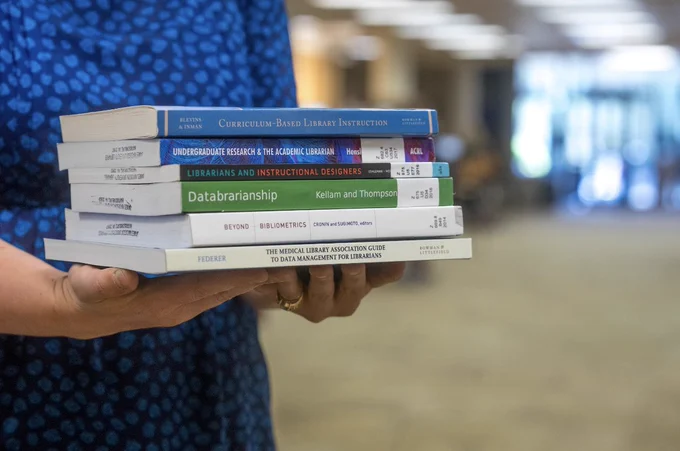 Psychology librarian Liz Chenevey holds six books about library science.