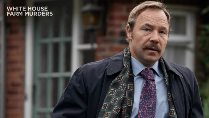 As DCI Thomas 'Taff' Jones in White House Farm Murders. He wears blue and pink floral tie with a blue dress shirt and long black overcoat. 