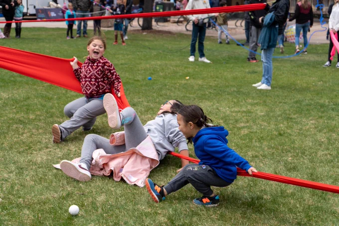 Three girls play with a giant rubber band at the Spring Science Extravaganza.