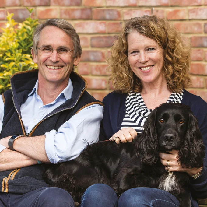 Bryn Parry sat outside on a bench with his wife Emma with their black dog on their lap.
