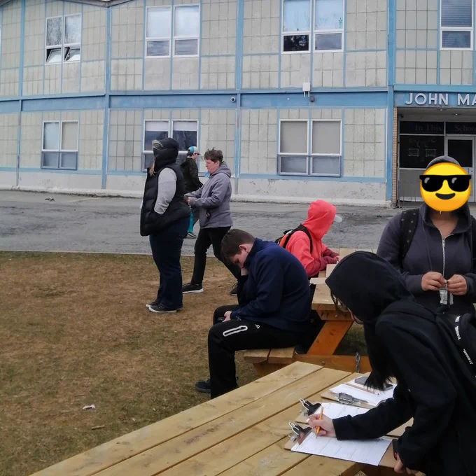 Students and staff stand in front of school doing math 