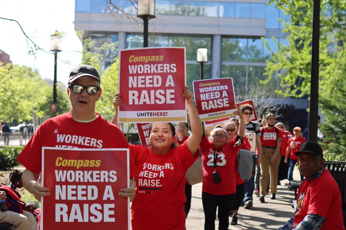 Workers hold Compass workers need a raise signs as they picket outside the Compass cafeteria at the World Bank