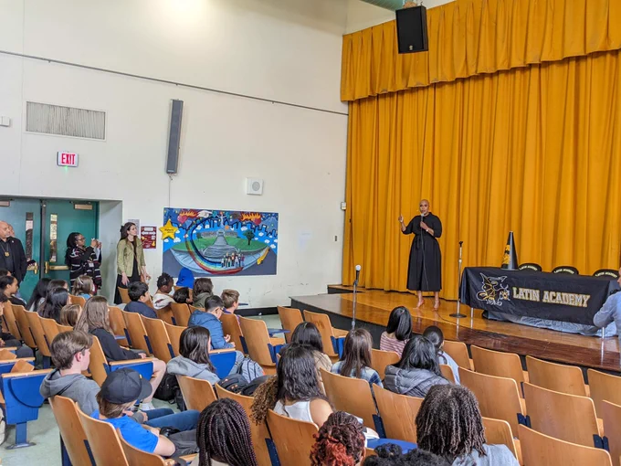 Ayanna speaking on stage in front of a crowd of students, educators, and partners at Boston Latin Academy.