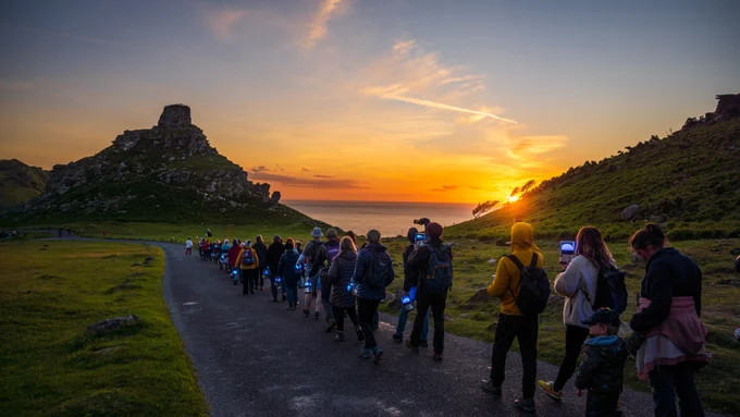 Lumenators part of Green Space Dark Skies walk along the coast as the sun sets in front of them.