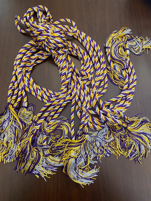 pile of tri-colored cords with tassels on the end. the cords are purple, silver and gold.