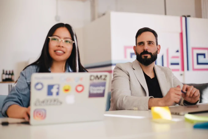 Two people sitting at a table paying attention to something off-camera.