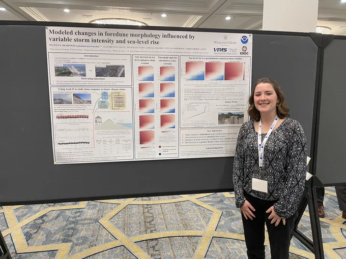undergrad selwyn heminway stands in front of her scientific poster at the Coastal Sediments conference. Poster shows results for dune modeling research.