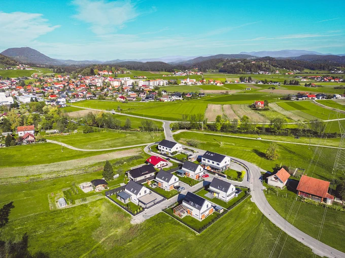 A photo of a small rural community surrounded by green fields and mountains.