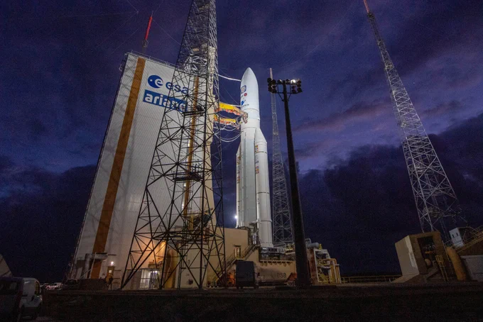 Ariane 5 VA260 rocket stands illuminated by spotlights before a dark sky ready for launch.
