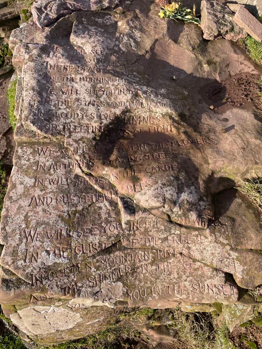 A poem for the dead etched into a large stone, resembling a grave.